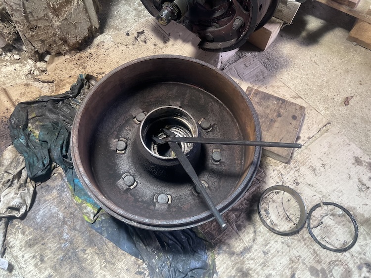 Using blacksmith’s tongs to loosen and remove the snap-ring, allowing the outer wheel bearing to be removed.